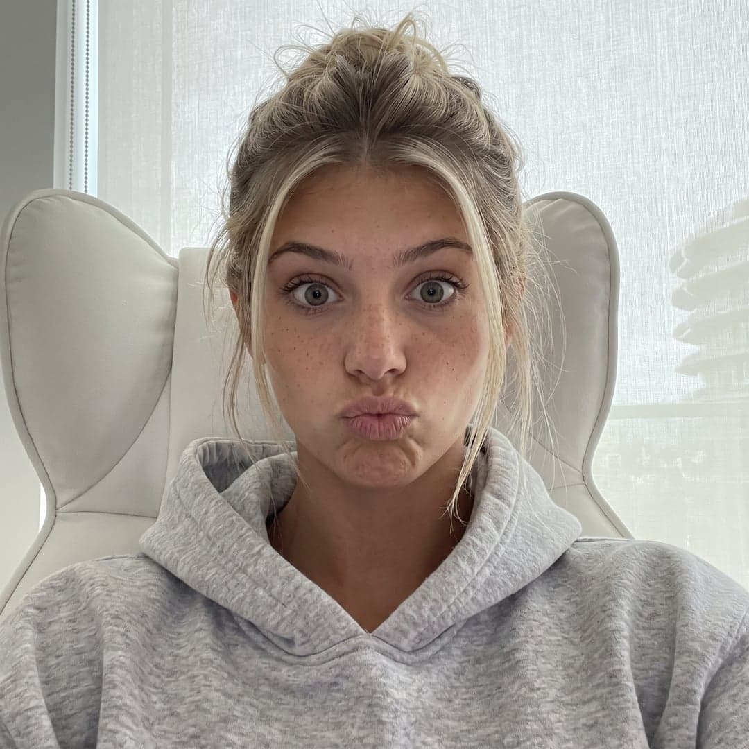 La même femme blonde détendue sur un canapé avec un sweat gris