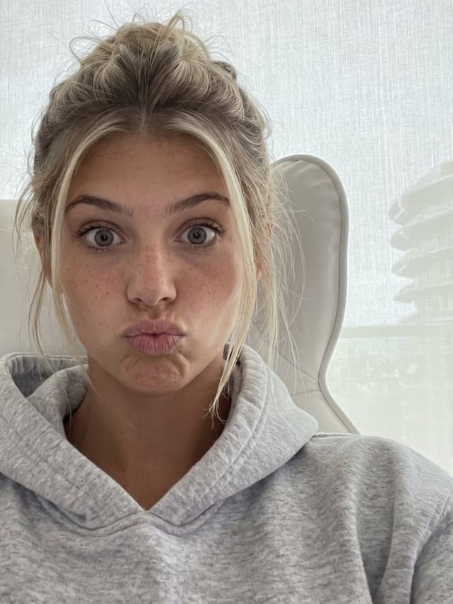 Influenceuse blonde qui rit dans une robe jaune